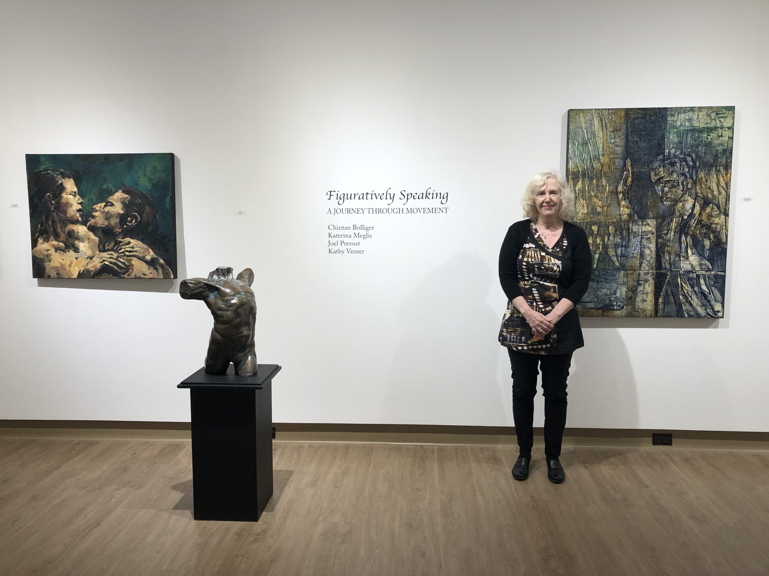 Pam Vickars standing with a painting in View Gallery